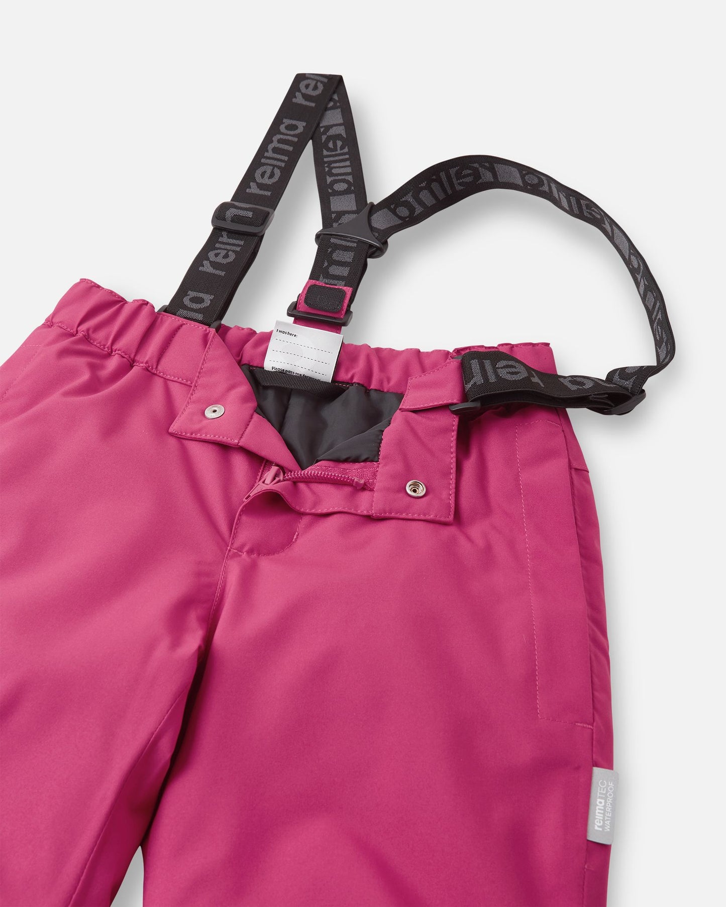 Close-up detail of the front waist on the rosy berry Reima Proxima kids' ski pants, showing the secure snap buttons, smooth zipper fly, elastic back waistband, and adjustable branded suspenders.