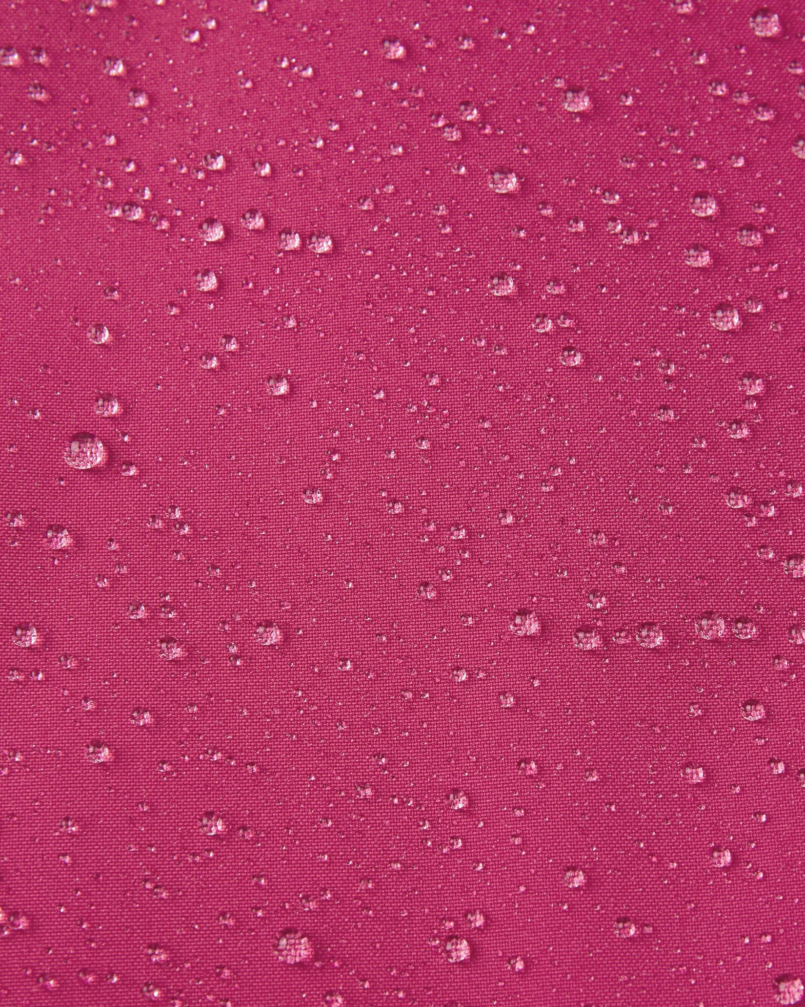 Macro close-up of water droplets actively beading and rolling off the rosy berry outer shell of the Reima Proxima kids' ski pants, visually highlighting the high-performance breathable and waterproof Reimatec technology.