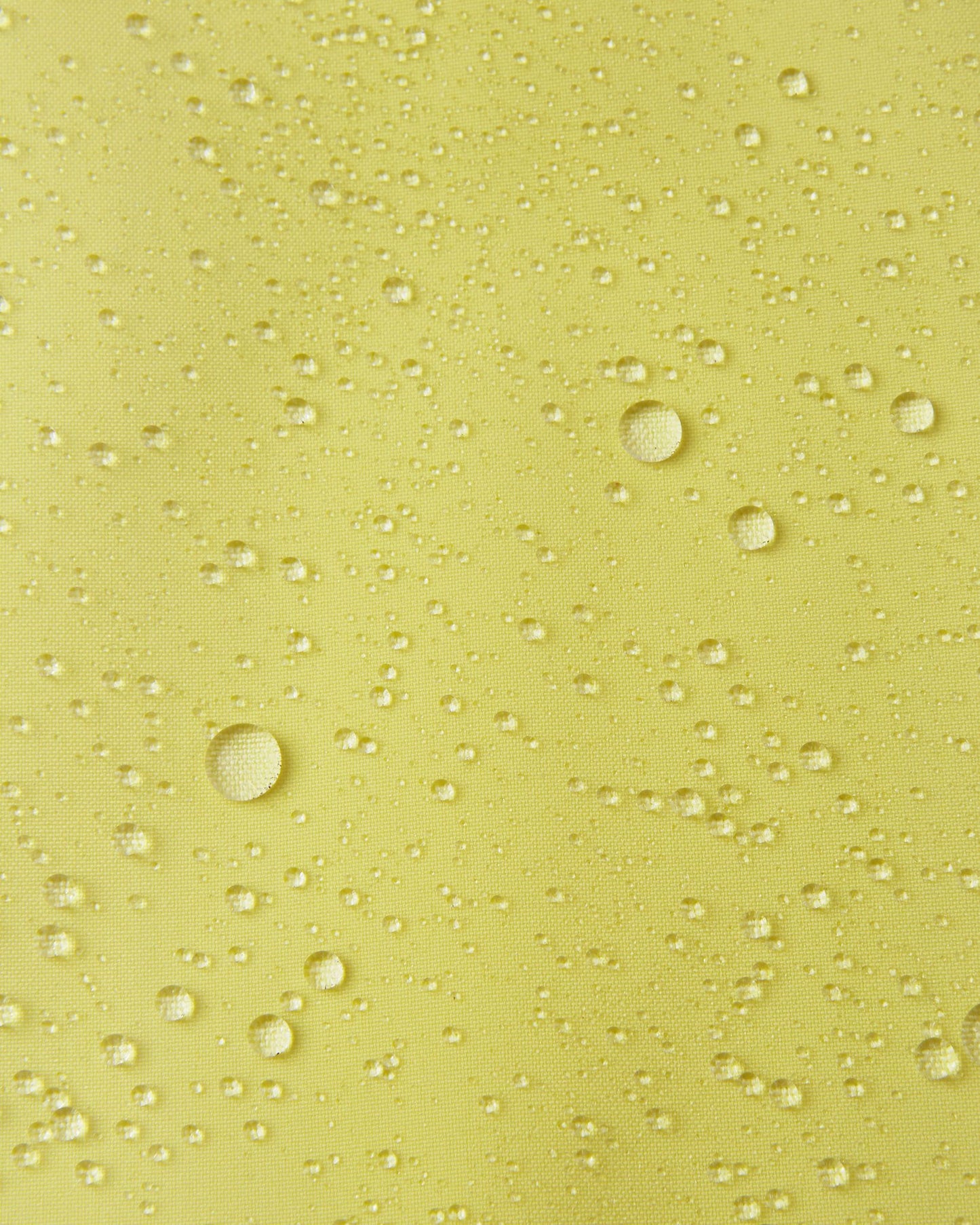 Macro close-up of water droplets actively beading and rolling off the bright yellow outer shell of the Reima Proxima kids' ski pants, visually highlighting the high-performance breathable and waterproof Reimatec technology.