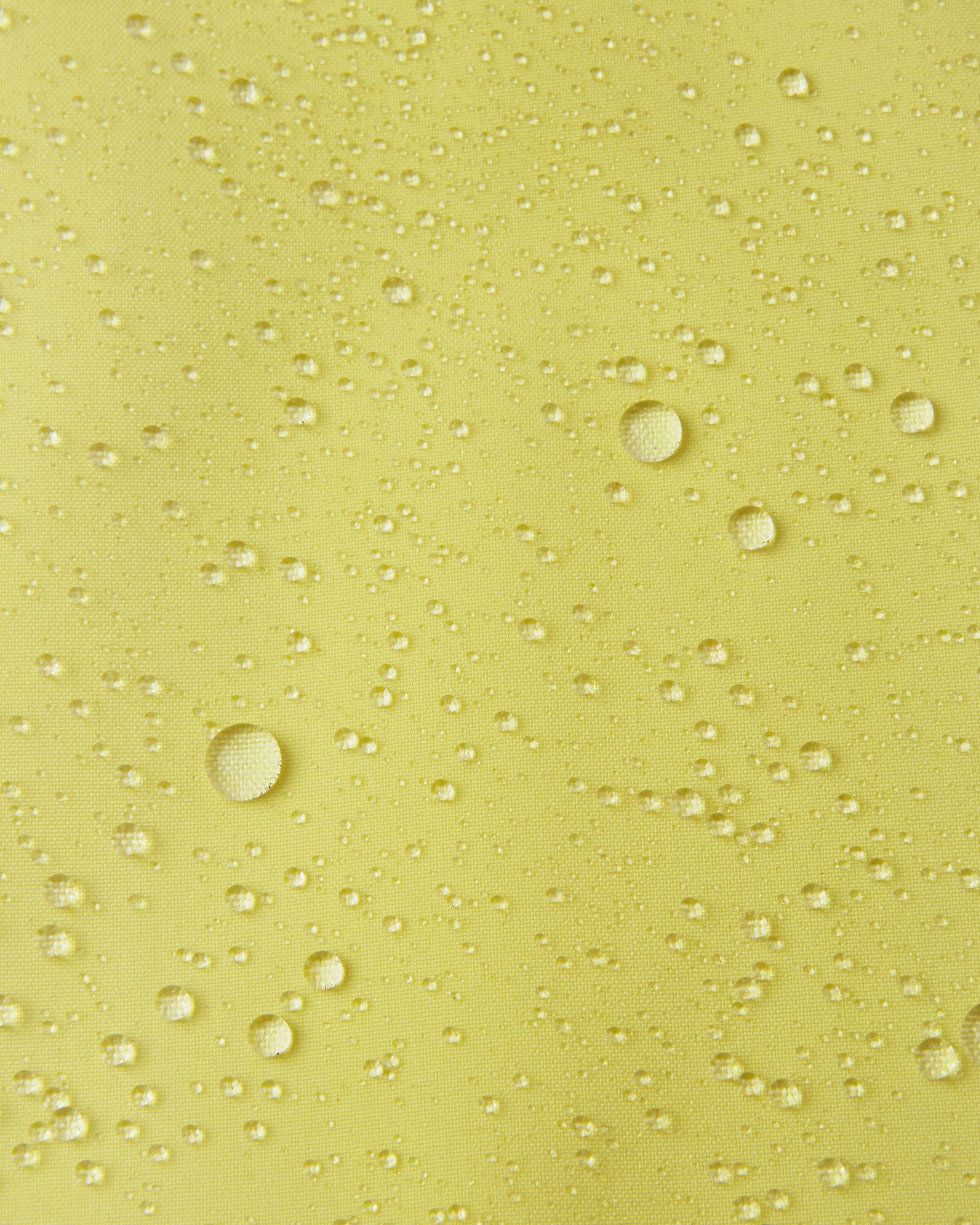 Macro close-up of water droplets actively beading and rolling off the bright yellow outer shell of the Reima Proxima kids' ski pants, visually highlighting the high-performance breathable and waterproof Reimatec technology.