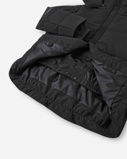 Interior view of the lower half of the black Reima Ranua kids' down ski jacket, featuring a smooth black lining, an adjustable elastic hem, and a built-in snow skirt with snap fasteners to completely block out snow and cold drafts.