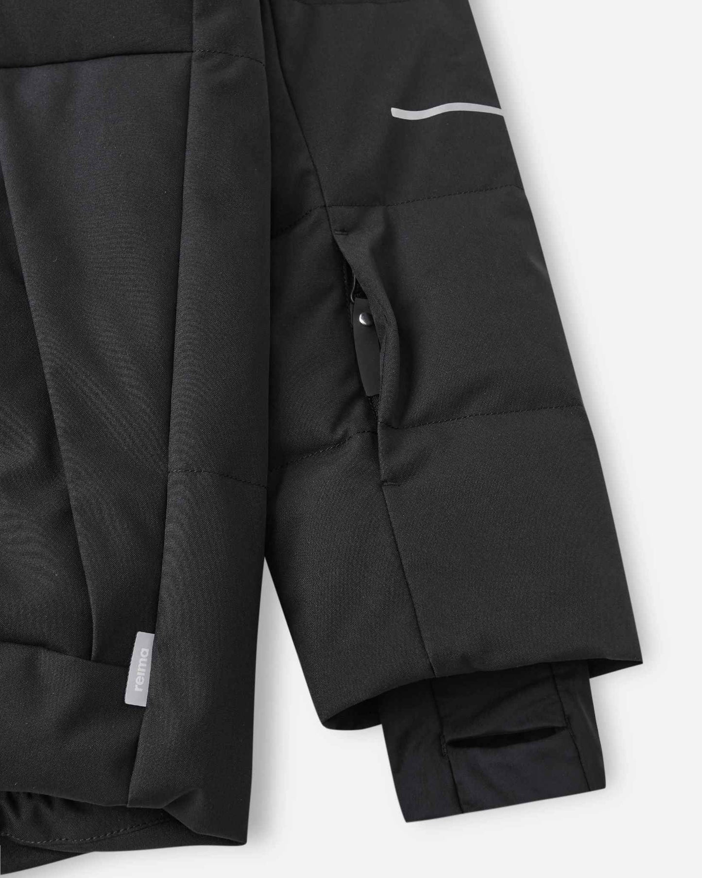 Close-up of the left sleeve on the Reima Ranua kids' down ski jacket in black, showing the hidden zippered ski pass pocket, reflective safety detailing, and the comfortable inner lycra thumbhole sleeve designed to seal out cold and snow.