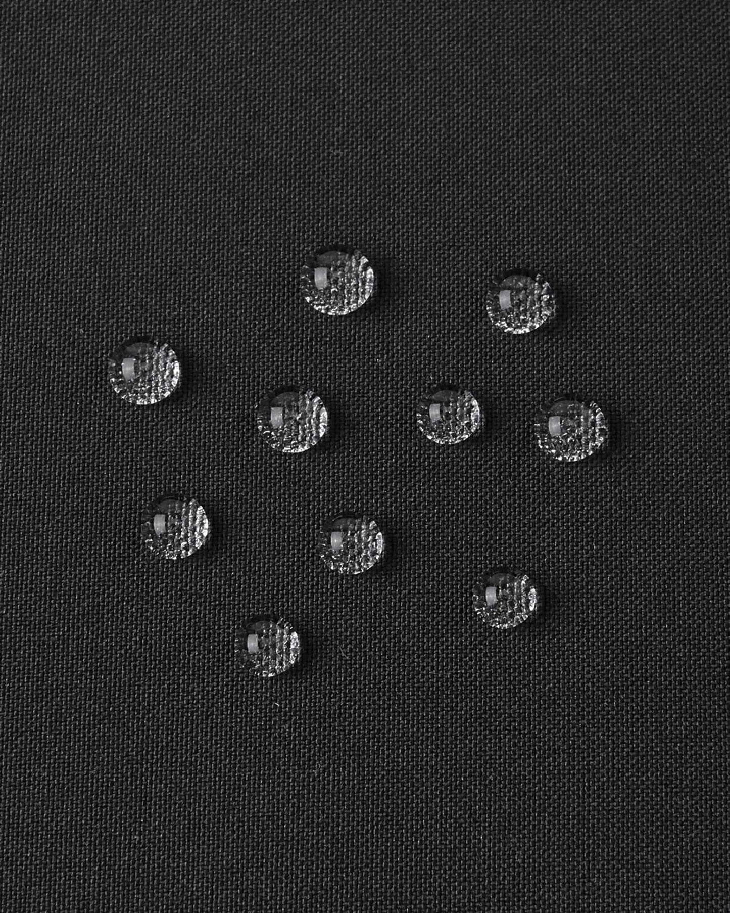 A detailed close-up texture shot of water droplets beading up cleanly on the black water-repellent fabric of a Reima Ranua kids' down ski jacket, demonstrating its durable weather-resistant performance for outdoor winter play.