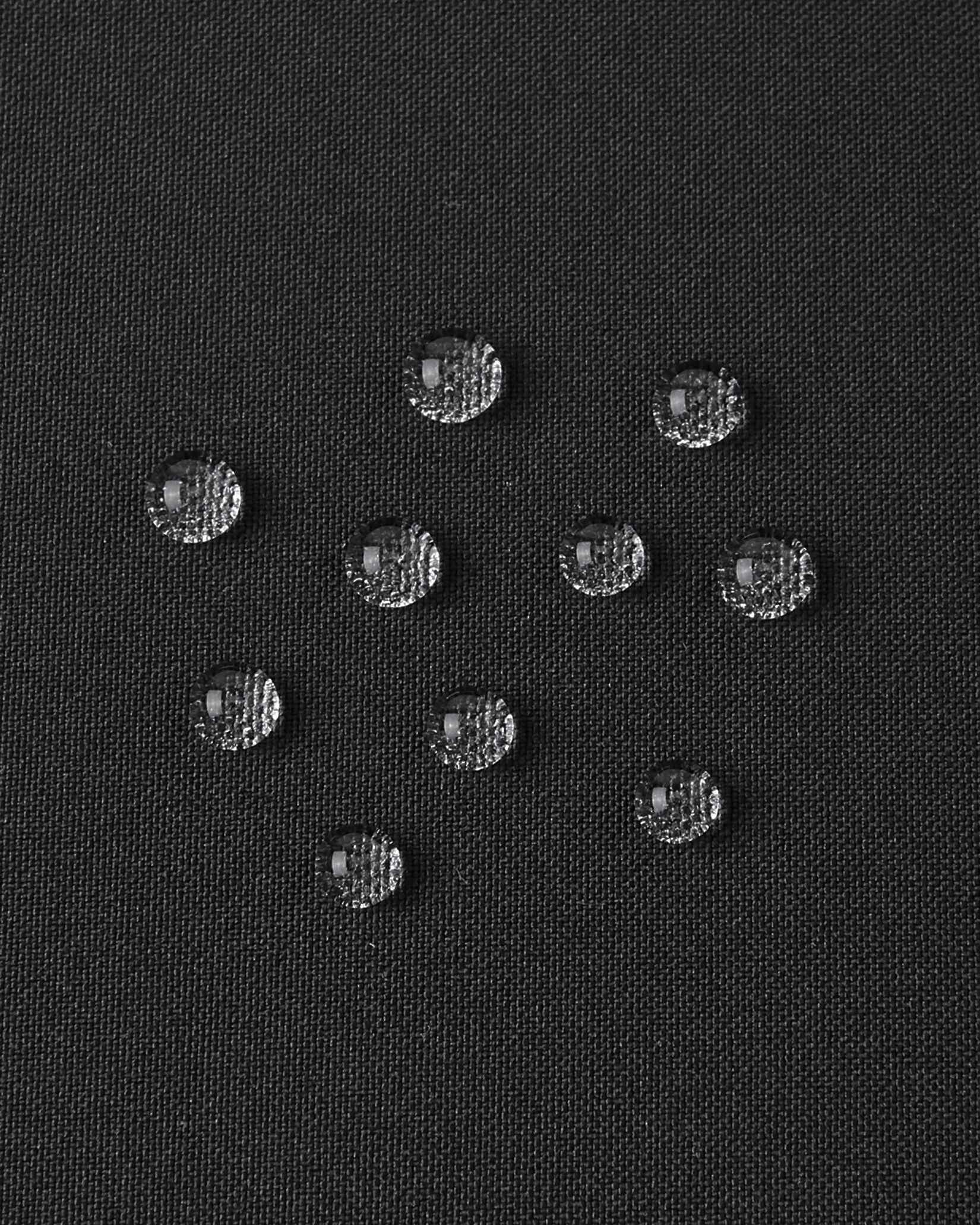 A detailed close-up texture shot of water droplets beading up cleanly on the black water-repellent fabric of a Reima Ranua kids' down ski jacket, demonstrating its durable weather-resistant performance for outdoor winter play.