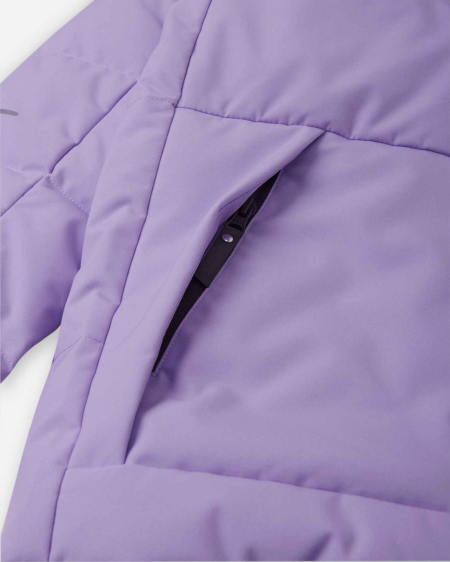 Close-up detail of the secure, hidden front zippered pocket on the quilted blooming lilac body of the Reima Ranua kids' down ski jacket, perfect for safely storing small items during outdoor winter play.