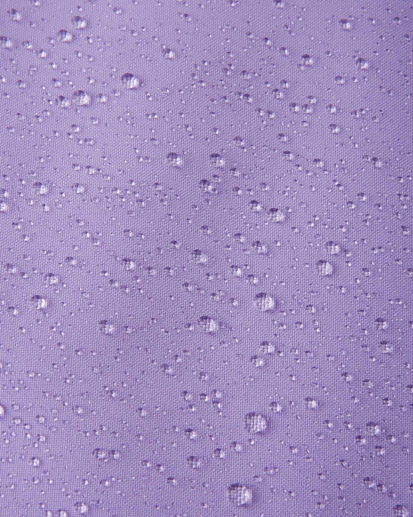 A detailed close-up texture shot of water droplets beading up cleanly on the blooming lilac water-repellent fabric of a Reima Ranua kids' down ski jacket, demonstrating its durable weather-resistant performance.