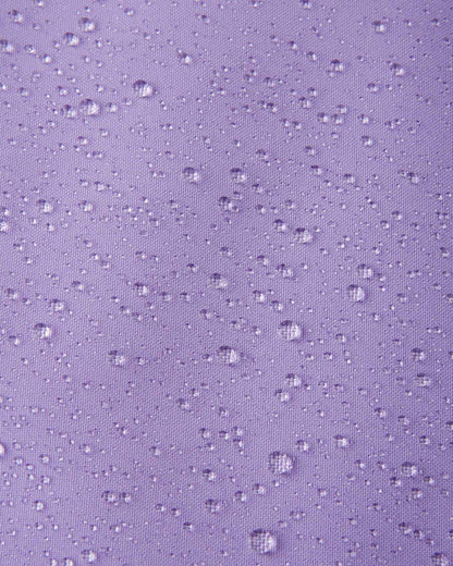 A detailed close-up texture shot of water droplets beading up cleanly on the blooming lilac water-repellent fabric of a Reima Ranua kids' down ski jacket, demonstrating its durable weather-resistant performance.