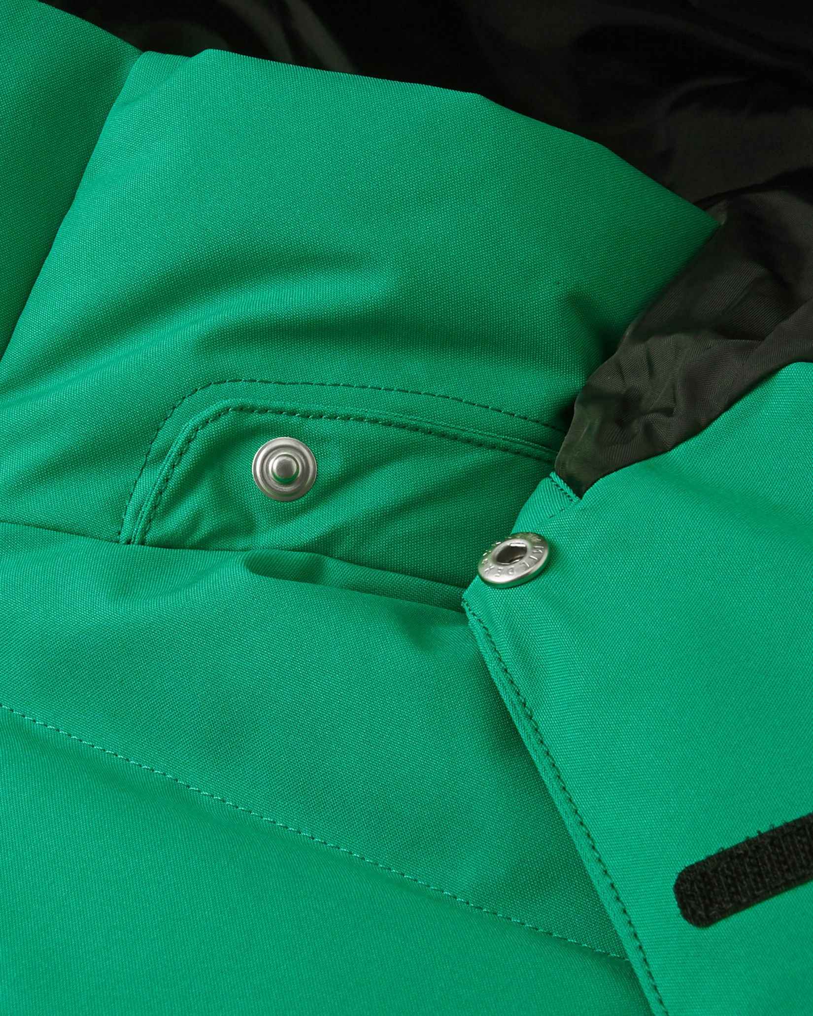 Close-up of the collar area on the Reima Ranua kids' down ski jacket in green, detailing the secure snap buttons used to attach the safe, easily removable winter hood.