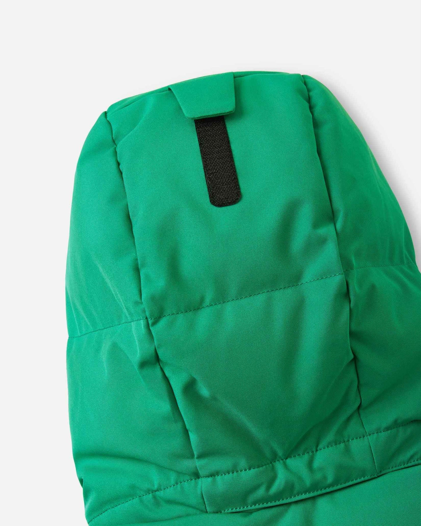 Close-up of the back of the insulated hood on the green Reima Ranua kids' down ski jacket, detailing the velcro adjustment tab used to customize the fit for maximum warmth and visibility.