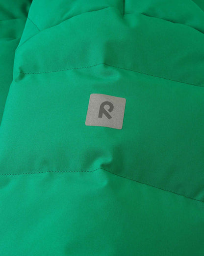Close-up detail of the green Reima Ranua kids' down ski jacket, highlighting the horizontal down insulation quilting and a square reflective Reima logo patch designed to enhance winter safety and visibility.