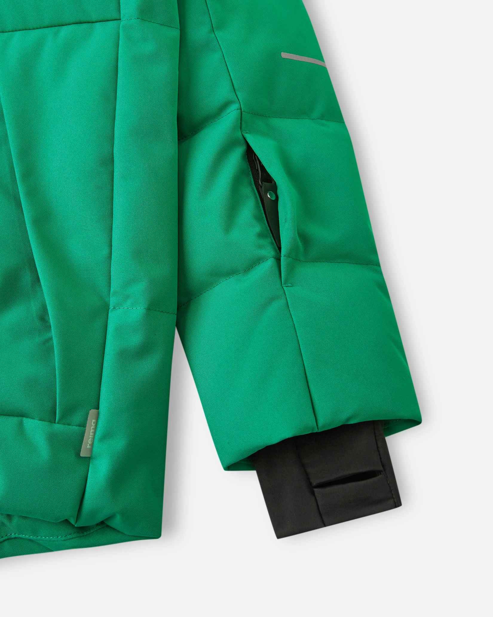 Close-up of the left sleeve on the Reima Ranua kids' down ski jacket in green, showing the hidden zippered ski pass pocket, an adjustable velcro cuff, and the comfortable inner lycra thumbhole sleeve designed to seal out snow.