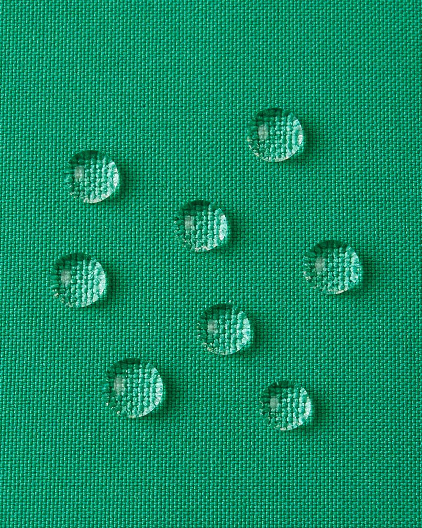 A detailed close-up texture shot of water droplets beading up cleanly on the green water-repellent fabric of a Reima Ranua kids' down ski jacket, demonstrating its durable weather-resistant performance for outdoor winter play.