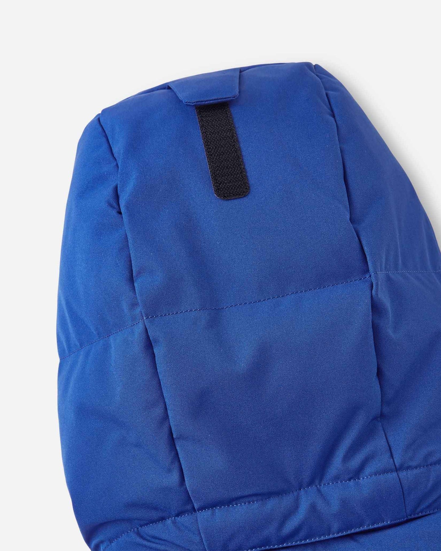 Close-up of the back of the insulated hood on the twilight blue Reima Ranua kids' down ski jacket, detailing the velcro adjustment tab used to customize the fit for maximum warmth and visibility.