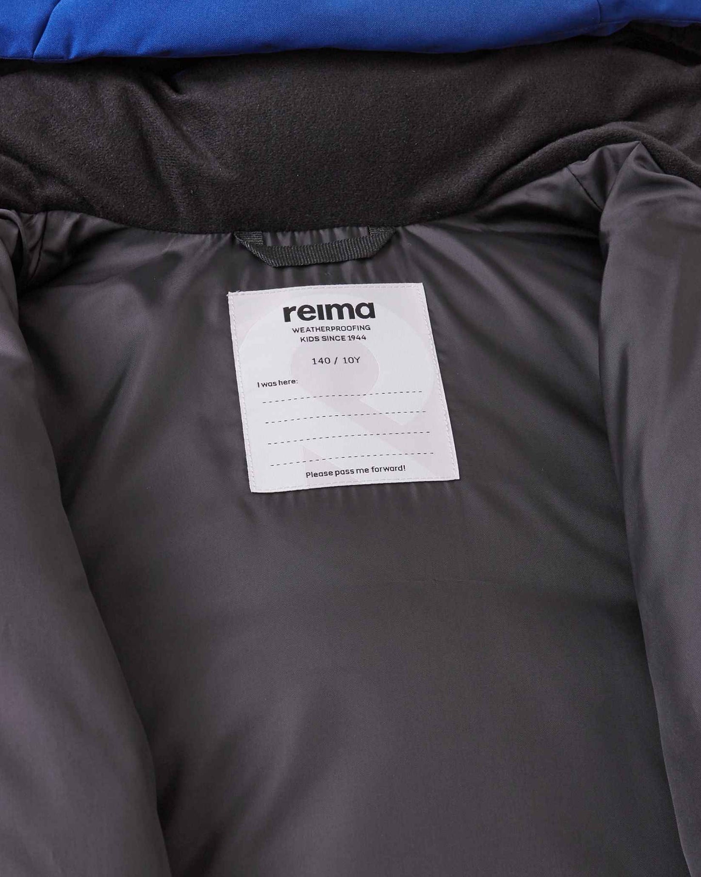 Interior view of the collar area on the Reima Ranua kids' down ski jacket in twilight blue, highlighting the smooth inner lining and a white Reima brand size tag, emphasizing its durable, high-quality design.