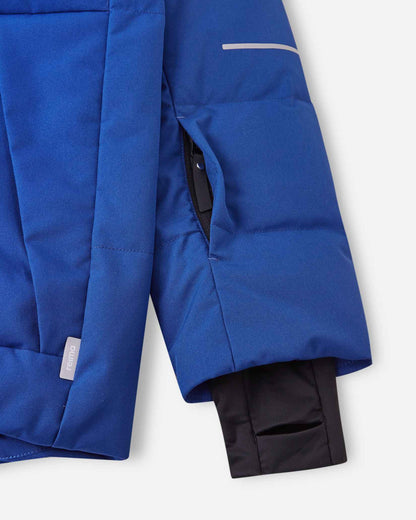 Close-up of the left sleeve on the Reima Ranua kids' down ski jacket in twilight blue, showing the hidden zippered ski pass pocket, reflective safety detailing, and the comfortable inner lycra thumbhole sleeve designed to seal out cold and snow.