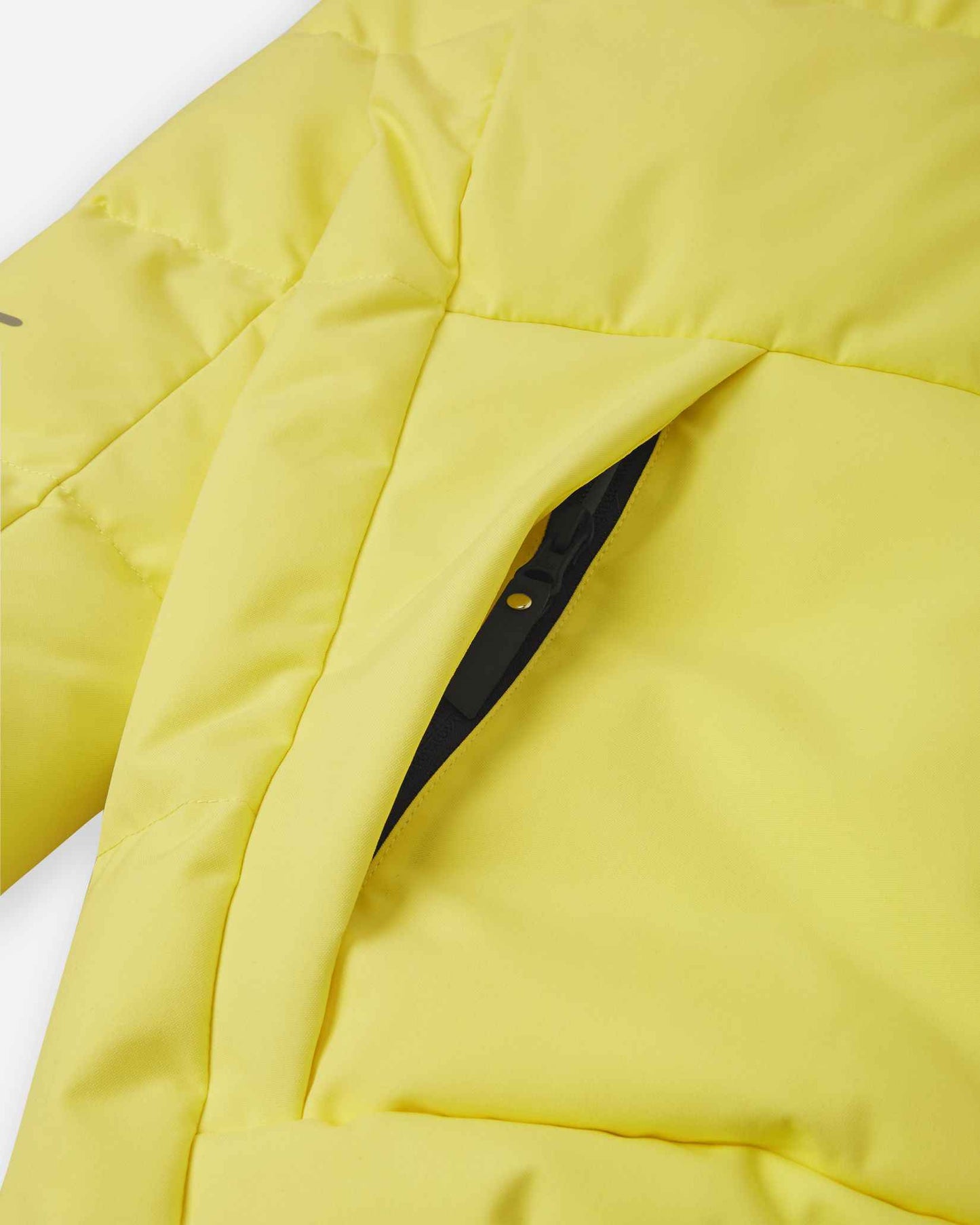 Close-up detail of the secure, hidden front zippered pocket on the quilted yellow body of the Reima Ranua kids' down ski jacket, perfect for safely storing small items.