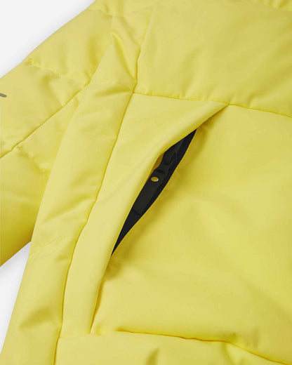Close-up detail of the secure, hidden front zippered pocket on the quilted yellow body of the Reima Ranua kids' down ski jacket, perfect for safely storing small items.
