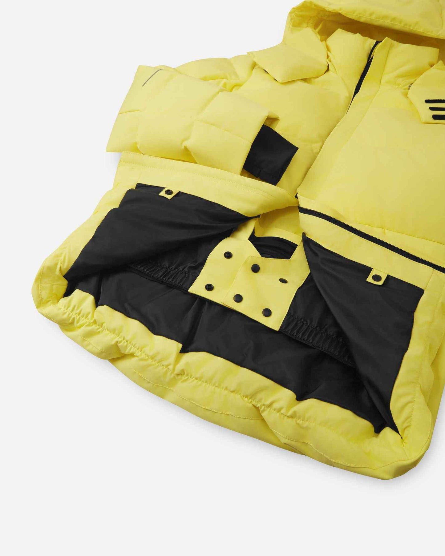 Interior view of the lower half of the yellow Reima Ranua kids' down ski jacket, featuring a smooth black lining, an adjustable elastic hem, and a built-in snow skirt with snap fasteners to completely block out snow and cold drafts.