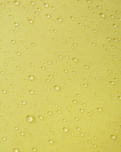 A detailed close-up texture shot of water droplets beading up cleanly on the bright yellow water-repellent fabric of a Reima Ranua kids' down ski jacket, demonstrating its durable weather-resistant performance for outdoor winter play.