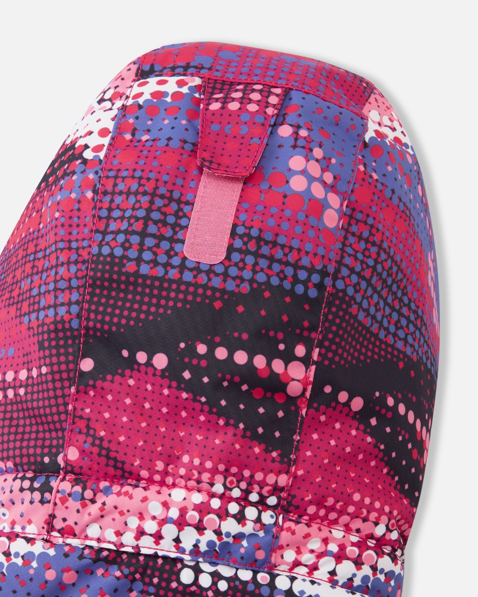 Detail shot of the back of the hood on the rosy berry Reima Reach girls' ski suit, highlighting the adjustable velcro tab that allows parents to easily customize the hood depth for a secure, windproof fit over a ski helmet or winter beanie.