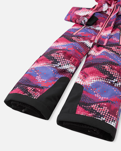 Close-up of the lower legs on the Reima Reach girls' winter ski suit in a rosy berry pattern, showcasing heavy-duty black reinforced kick panels and elastic inner snow gaiters designed to seal tightly over ski boots and block out deep powder.