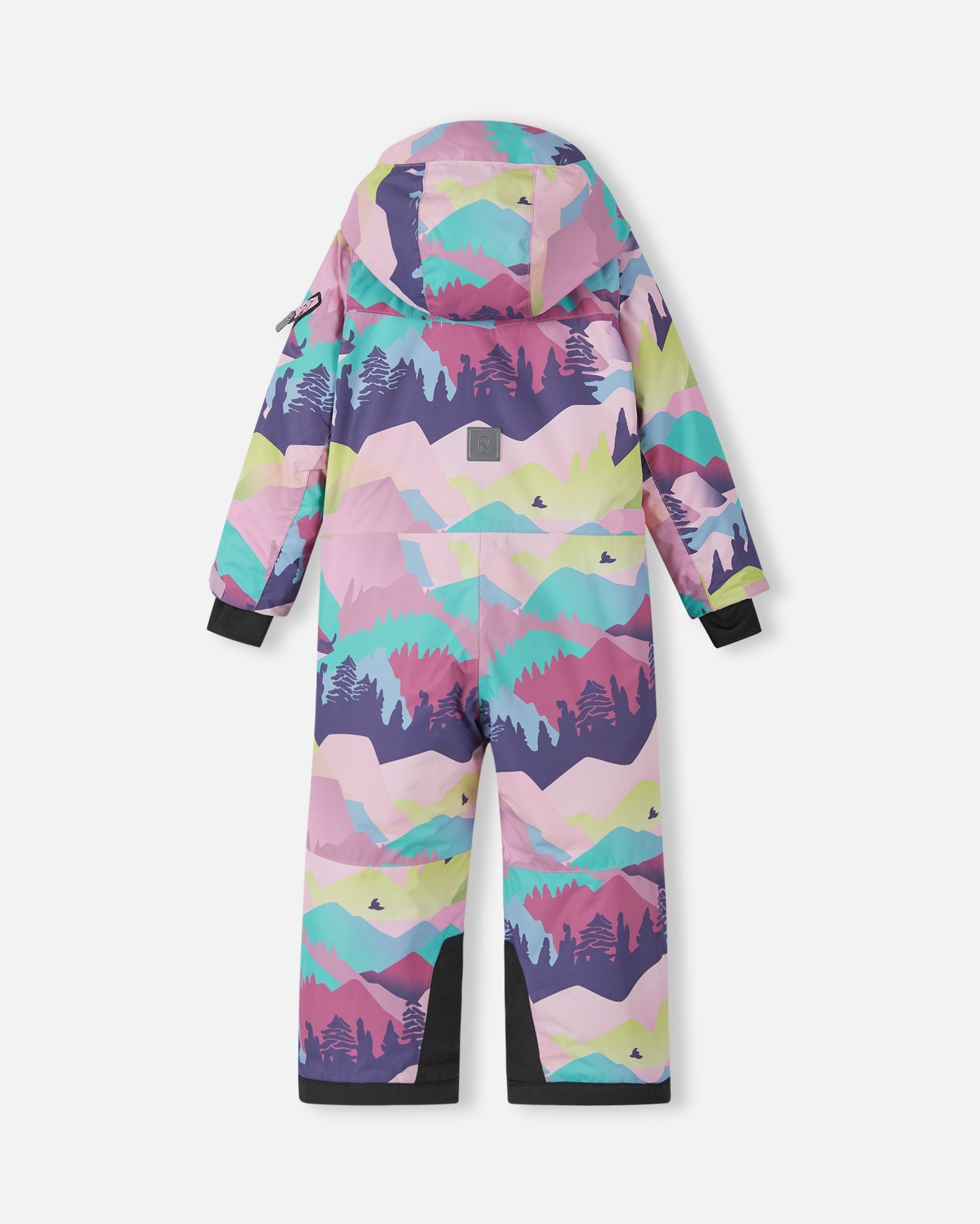 Back view of the Reima Reach kids' winter ski suit in a vibrant pink and purple mountain pattern, showing the attached hood, a reflective safety patch in the center back, and highly durable black reinforced fabric at the lower inner ankles to protect against ski edges.