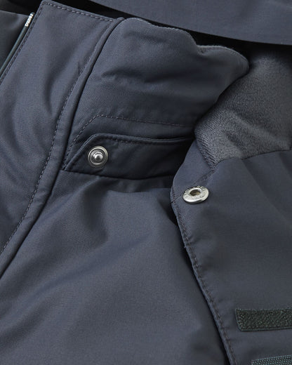 Close-up view of the child-safe snap button attachments on the soft black Reima Reach ski suit collar, demonstrating the easy-release detachable hood mechanism designed to prevent snagging for winter playground safety.