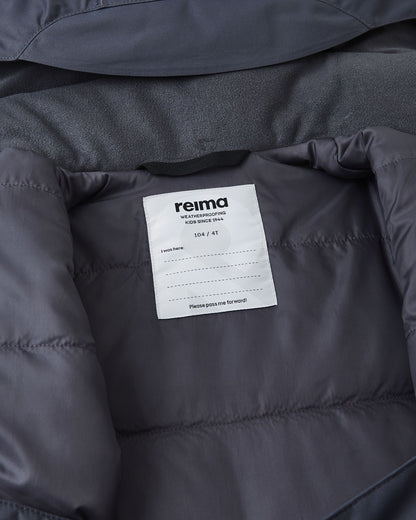 Inside collar view of the soft black Reima Reach ski suit, displaying the cozy fleece lining to prevent chin chafing and a dedicated Reima name tag with multiple lines to encourage sustainable hand-me-downs.