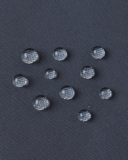 Macro close-up of water droplets tightly beading on the soft black Reimatec fabric of the Reima Reach kids' ski suit, demonstrating its extreme high-performance waterproof and weather-resistant surface capabilities.