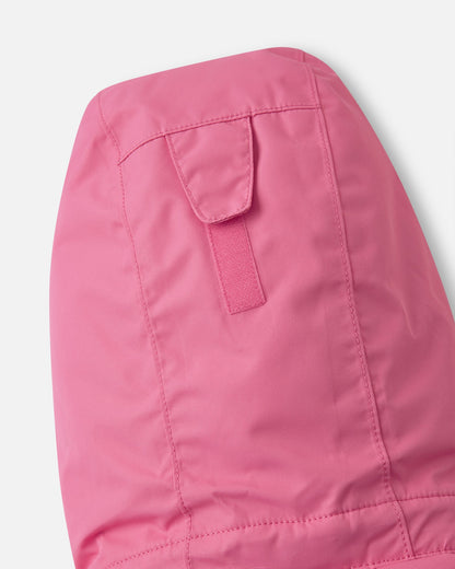 Detail shot of the back of the hood on the soft coral Reima Reach kids' ski suit, highlighting the adjustable velcro tab that customizes hood depth for a secure fit over ski helmets or beanies.