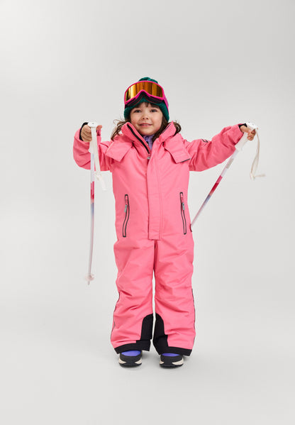 Young girl holding ski poles and wearing the soft coral Reima Reach waterproof ski suit, demonstrating its flexible, ergonomic fit designed specifically for active alpine skiing and winter sports.
