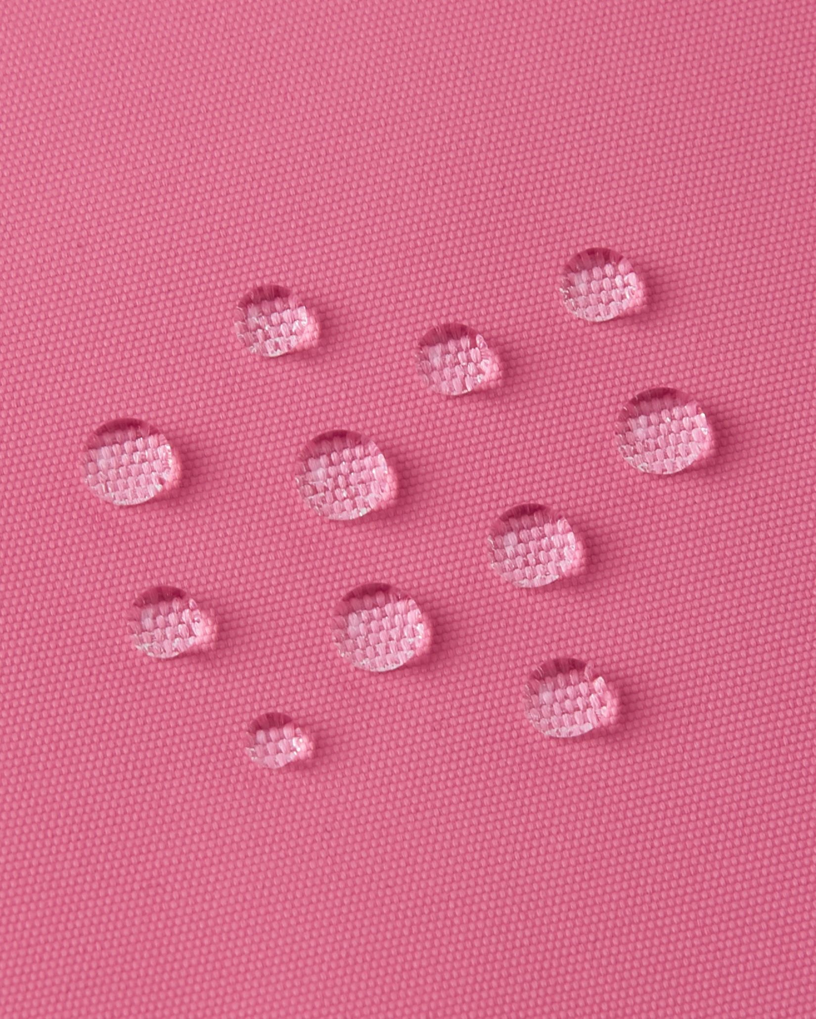 Macro close-up of water droplets tightly beading on the soft coral Reimatec fabric of the Reima Reach kids' ski suit, demonstrating its high-performance waterproof and weather-resistant surface.