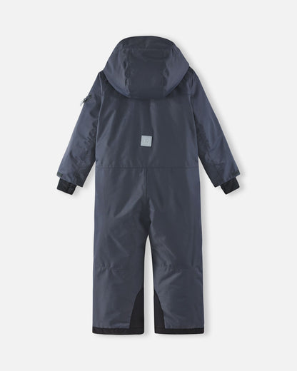Full back view of the Reima Reach kids' ski suit in soft black, highlighting the attached winter hood, a high-visibility reflective safety patch centered on the back, and heavy-duty black reinforced seat and ankle panels.