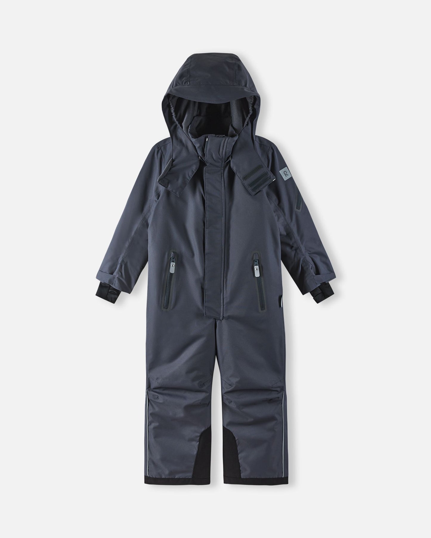 Full front view of the soft black Reima Reach kids' winter ski suit with the helmet-compatible hood pulled up, demonstrating the full-coverage weather protection and ergonomic design ideal for active winter sports.