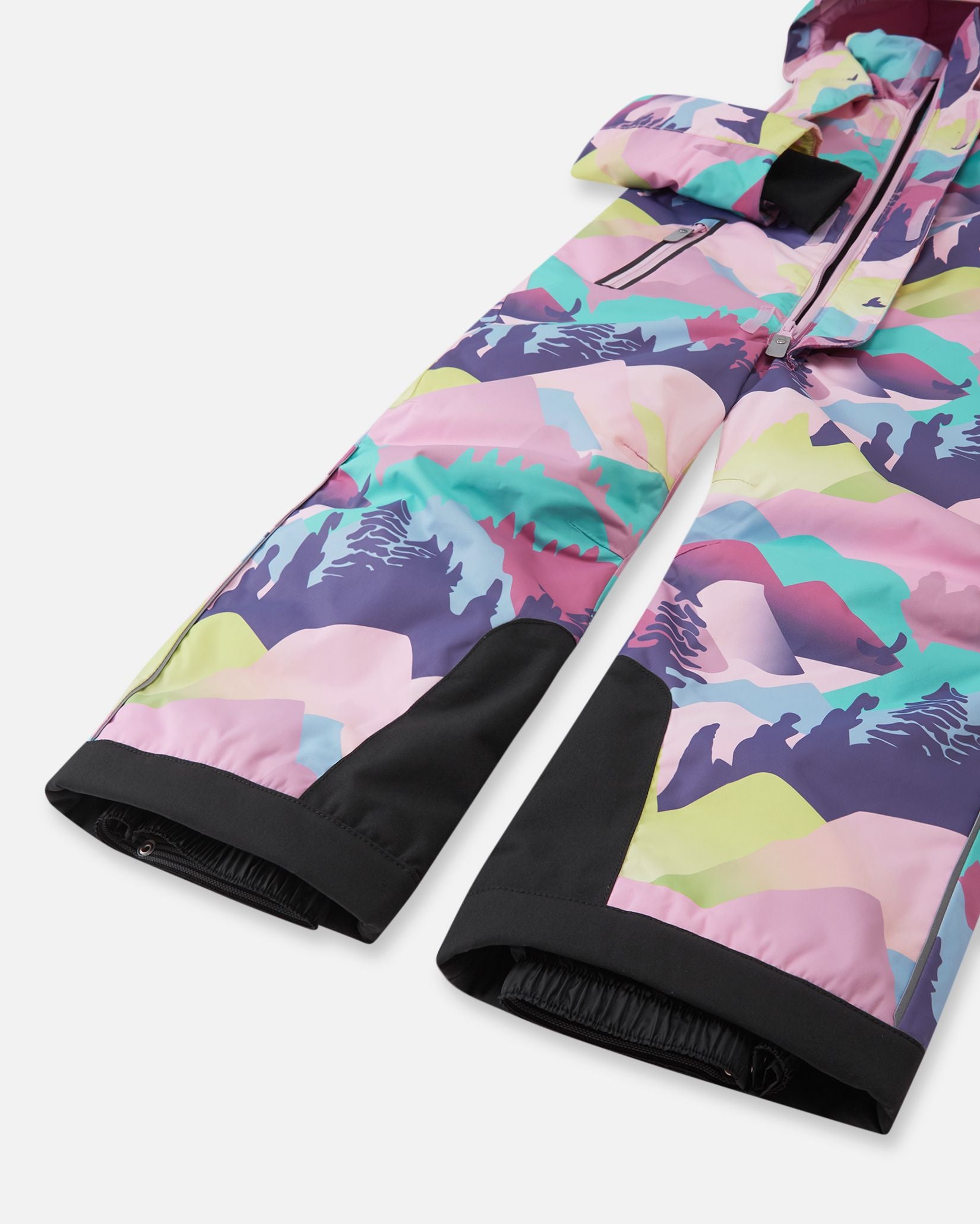 Detail shot of the lower legs on the Reima Reach kids' ski suit, showcasing the heavy-duty black reinforced kick patches to prevent fraying, alongside the inner elastic snow gaiters designed to stretch securely over ski boots to keep snow out.