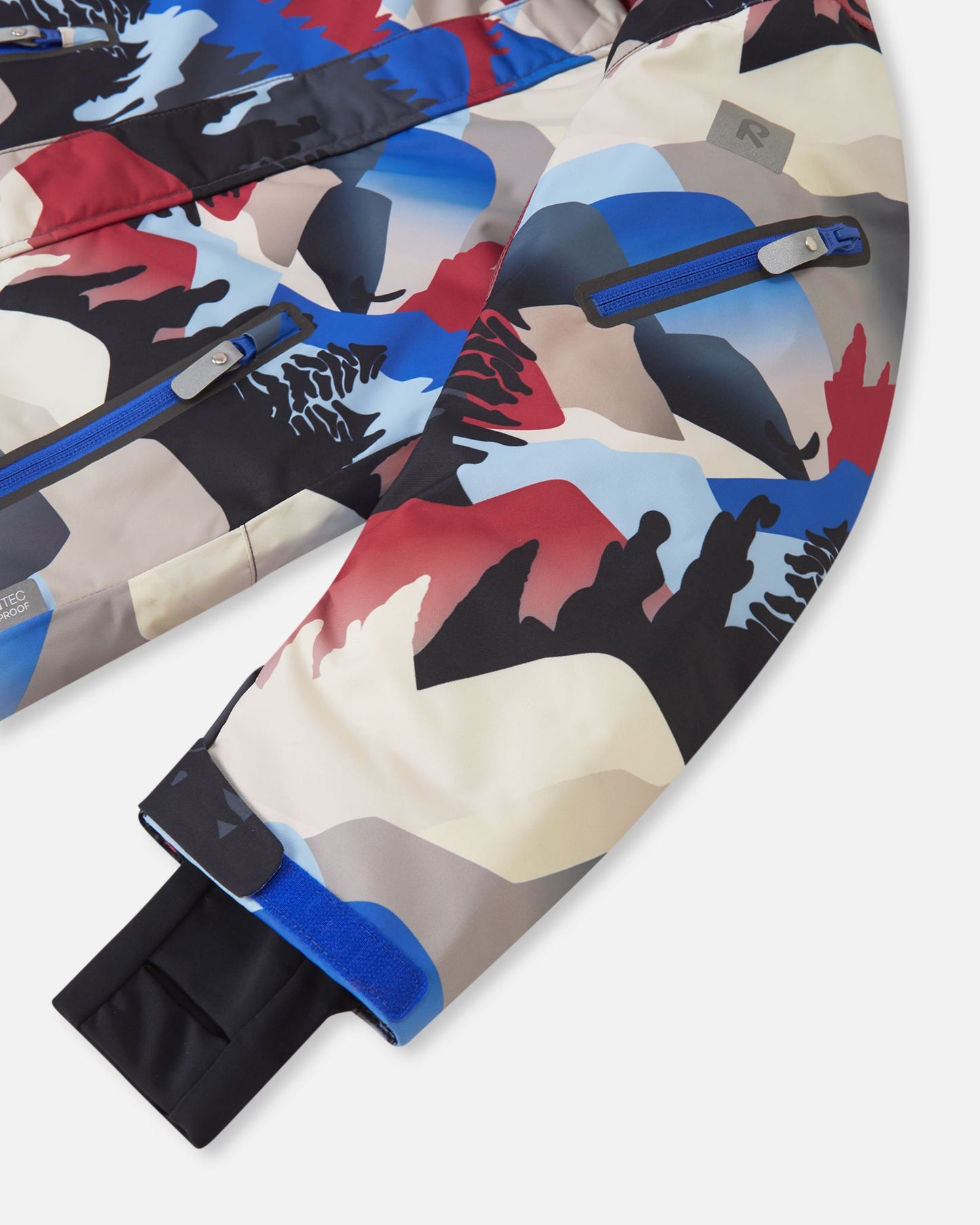 Close-up of the Reima Reach ski suit sleeve in the soft black mountain print, featuring a convenient zippered ski pass pocket on the forearm, an adjustable velcro outer cuff, and a snug inner stretch cuff to lock in warmth and block wind.