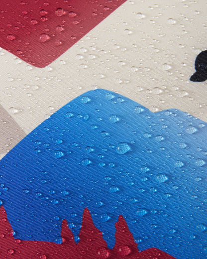Macro close-up of water droplets tightly beading and resting on the blue, red, and cream Reimatec fabric of the Reach ski suit, clearly demonstrating the material's advanced waterproof and weather-resistant performance for winter conditions.