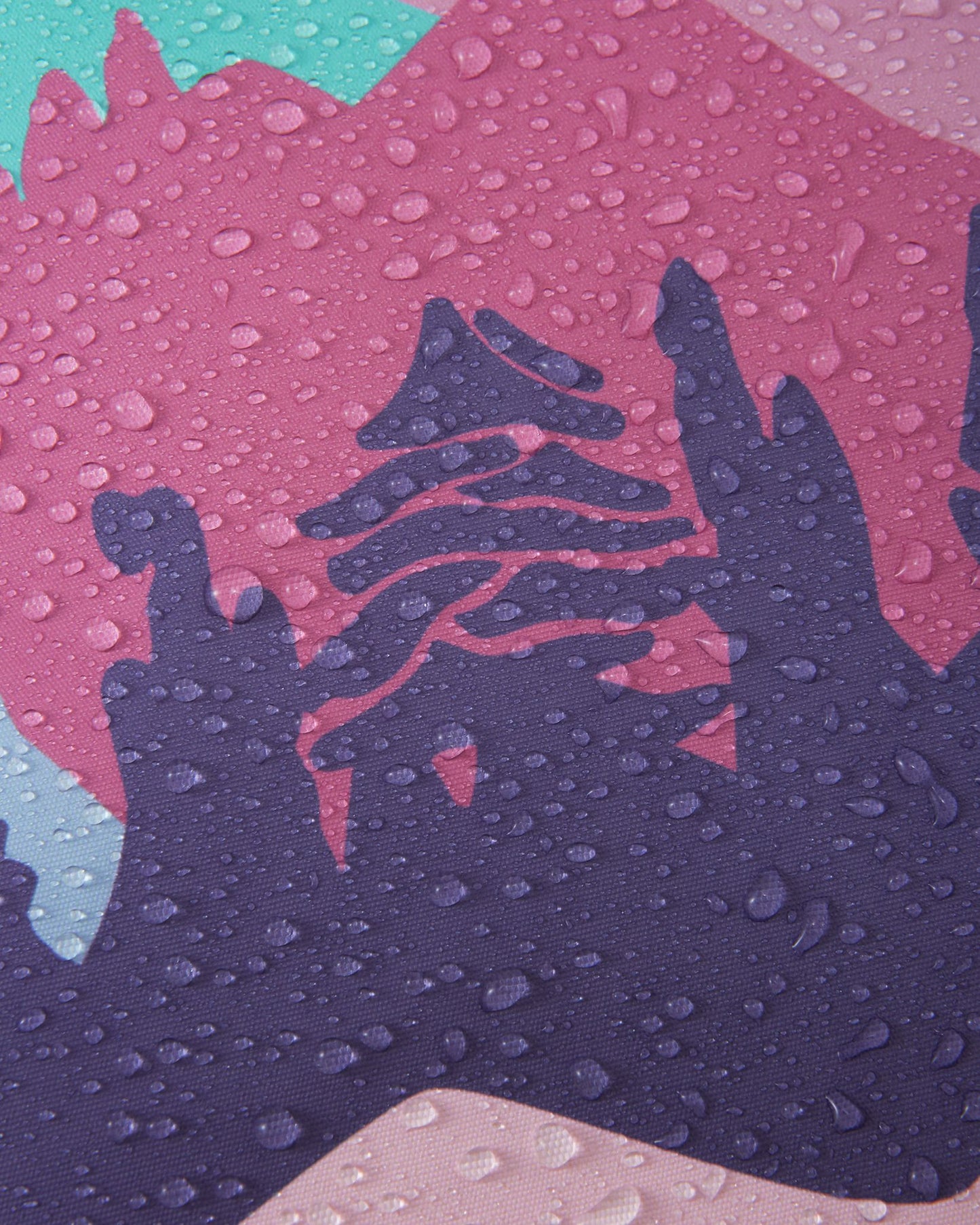 Macro close-up of water droplets tightly beading and resting on the purple and pink Reimatec fabric of the Reach ski suit, clearly demonstrating the material's advanced waterproof and weather-resistant properties.