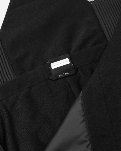 Interior detail view of the black Reima Rehti kids' snow bibs, showing the integrated size and customizable "I was here" name tag label inside the upper vest for easy identification at ski school or winter camp.