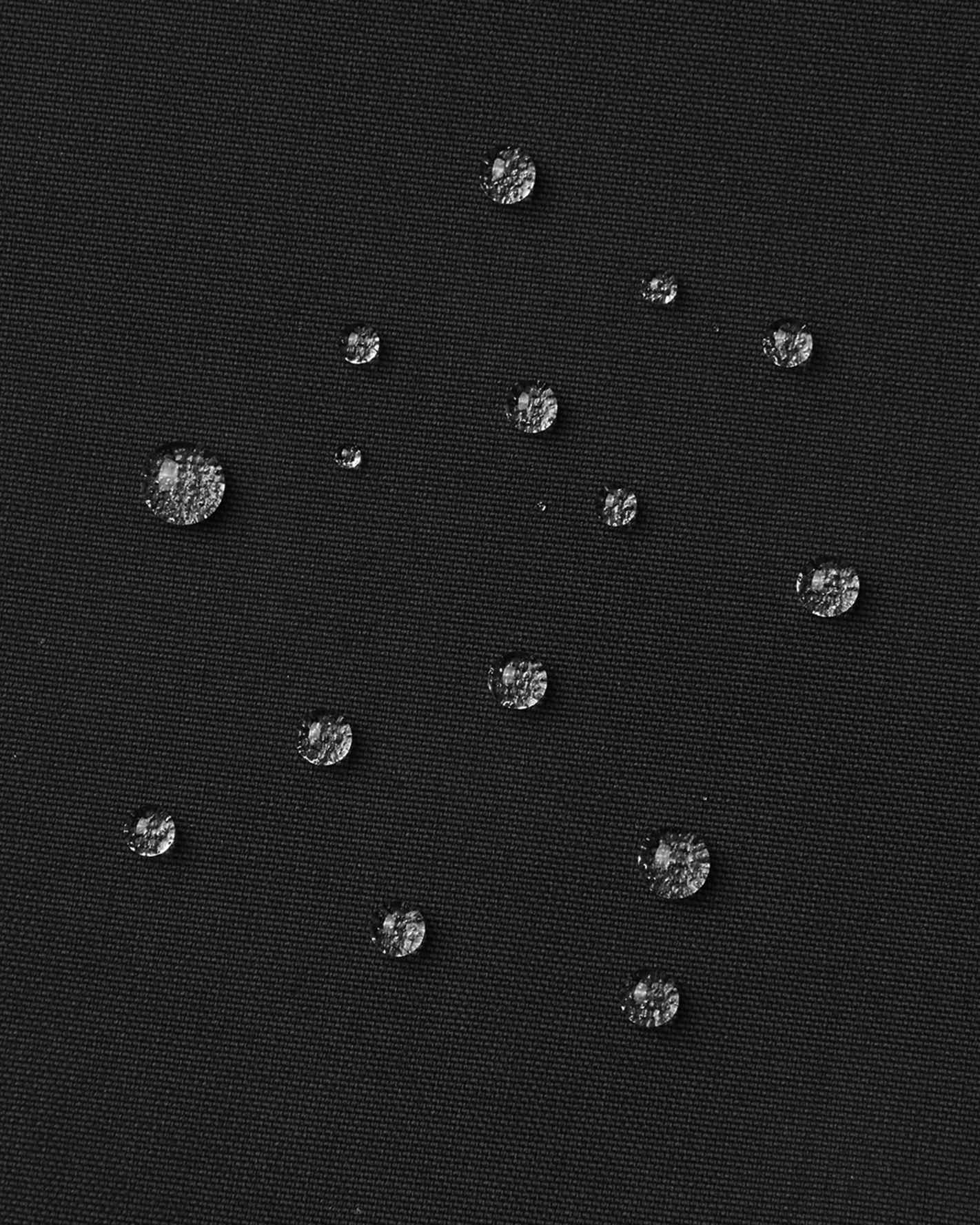 Macro close-up of water droplets actively beading and rolling off the black textured outer shell of the Reima Rehti kids' ski bibs, visually highlighting the high-performance breathable and waterproof Reimatec technology.