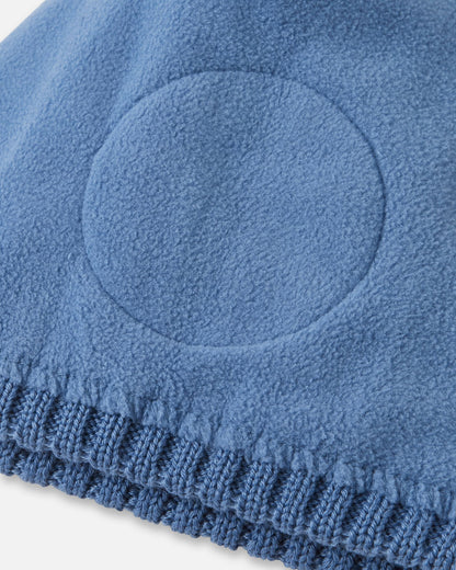 Detailed interior view of the blue ocean Reima Routii kids' beanie. The image reveals the fully lined, soft thermal fleece interior and the specialized circular windproof earpiece inserts designed to protect children's ears from cold winter winds.