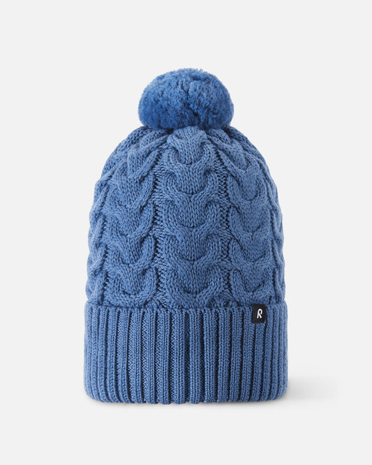 Front flat lay view of the blue ocean Reima Routii kids' knitted winter beanie. The image highlights the classic cable knit design, a wide ribbed fold-up hem for a secure fit, a matching yarn pom-pom, and the small black Reima logo tag.