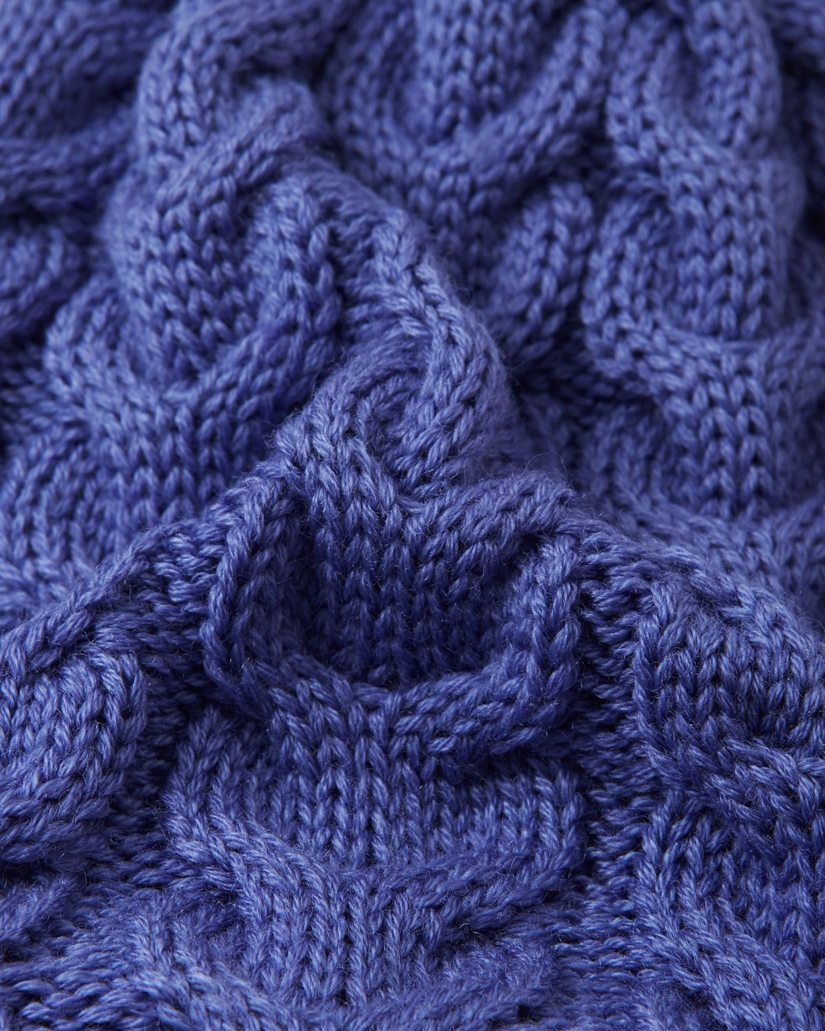 Macro close-up of the thick, intricate cable knit structure on the breezy violet Reima Routii kids' winter hat, demonstrating the high-quality texture and flexibility of the warm merino wool-blend yarn.