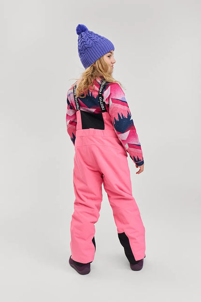 Back view of a child wearing the Reima Routii kids knitted merino wool beanie in breezy violet, paired with pink ski apparel.