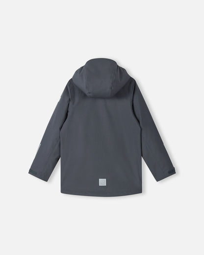 Back view of the Reima Saarela kids waterproof fall jacket in soft black, with the detachable protective hood attached and visible reflective patches on the lower back and sleeve. This jacket is Iisisti fleece compatible via a zip-in system.