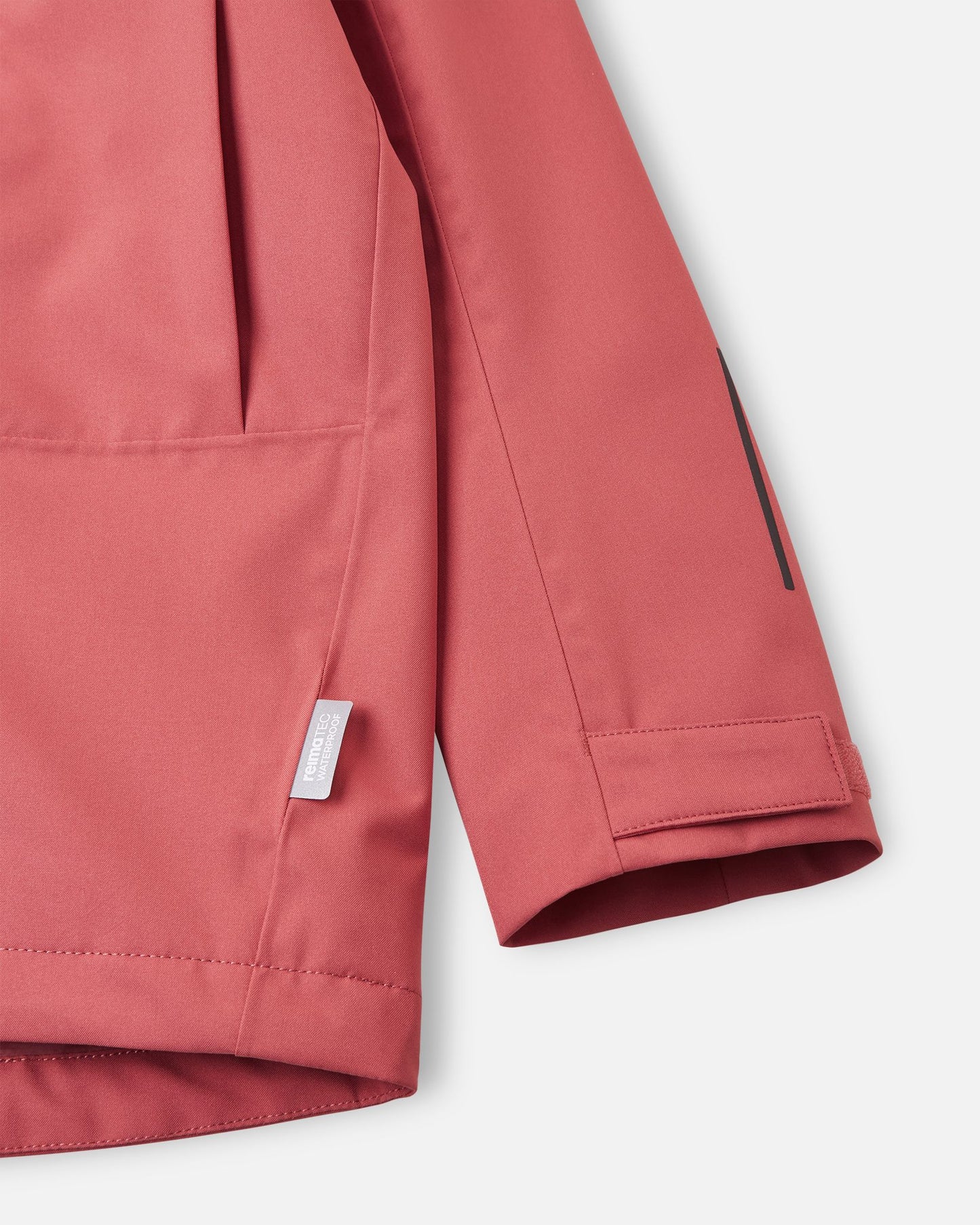Detailed close-up of the sleeve on the Reima Saarela kids' red clay shell jacket, focusing on the adjustable hook-and-loop cuff, reflective safety detail, and the Reimatec waterproof technology tag.