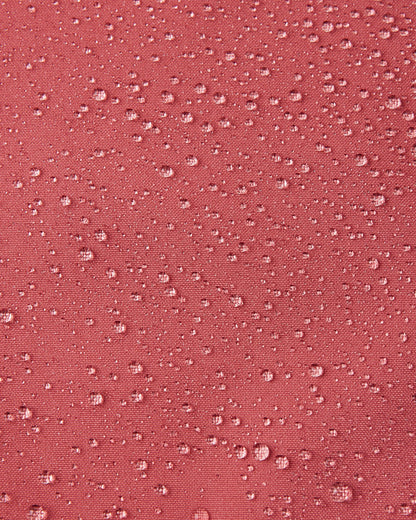Macro close-up of water droplets beading up and rolling off the surface of the Reima Saarela kids' red clay shell jacket, demonstrating the highly waterproof and dirt-repellent Reimatec material.