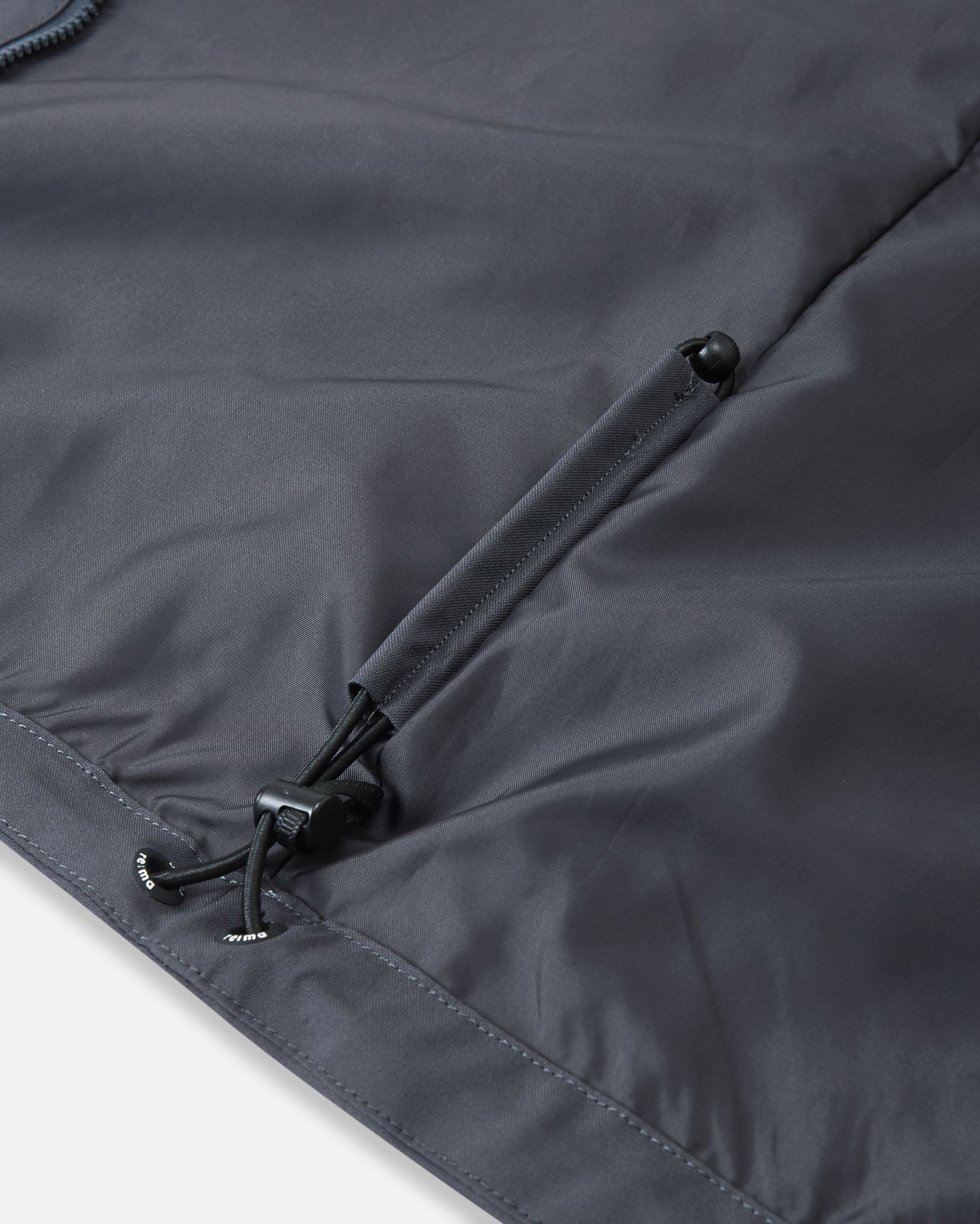 Close-up of the interior adjustable bungee cord hem on the Reima Saarela kids waterproof jacket, designed to seal out cold wind.