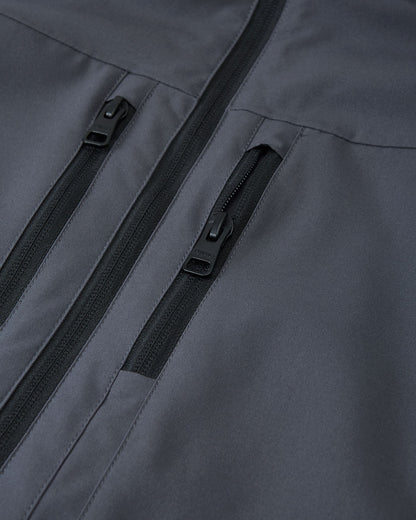 Close-up of the two secure, vertical zippered chest pockets on the Reima Saarela waterproof jacket in soft black.