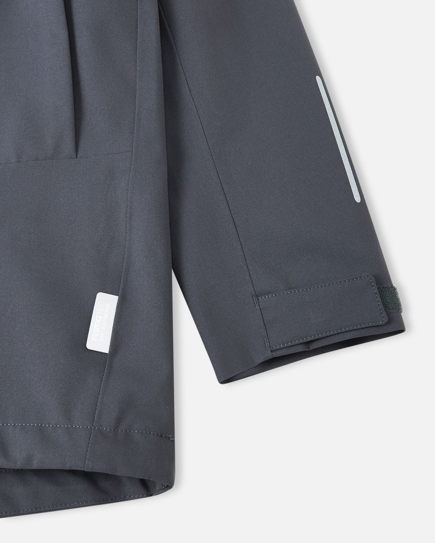 Close-up of the adjustable velcro sleeve cuff and safety reflective detailing on the soft black Reima Saarela kids waterproof jacket.